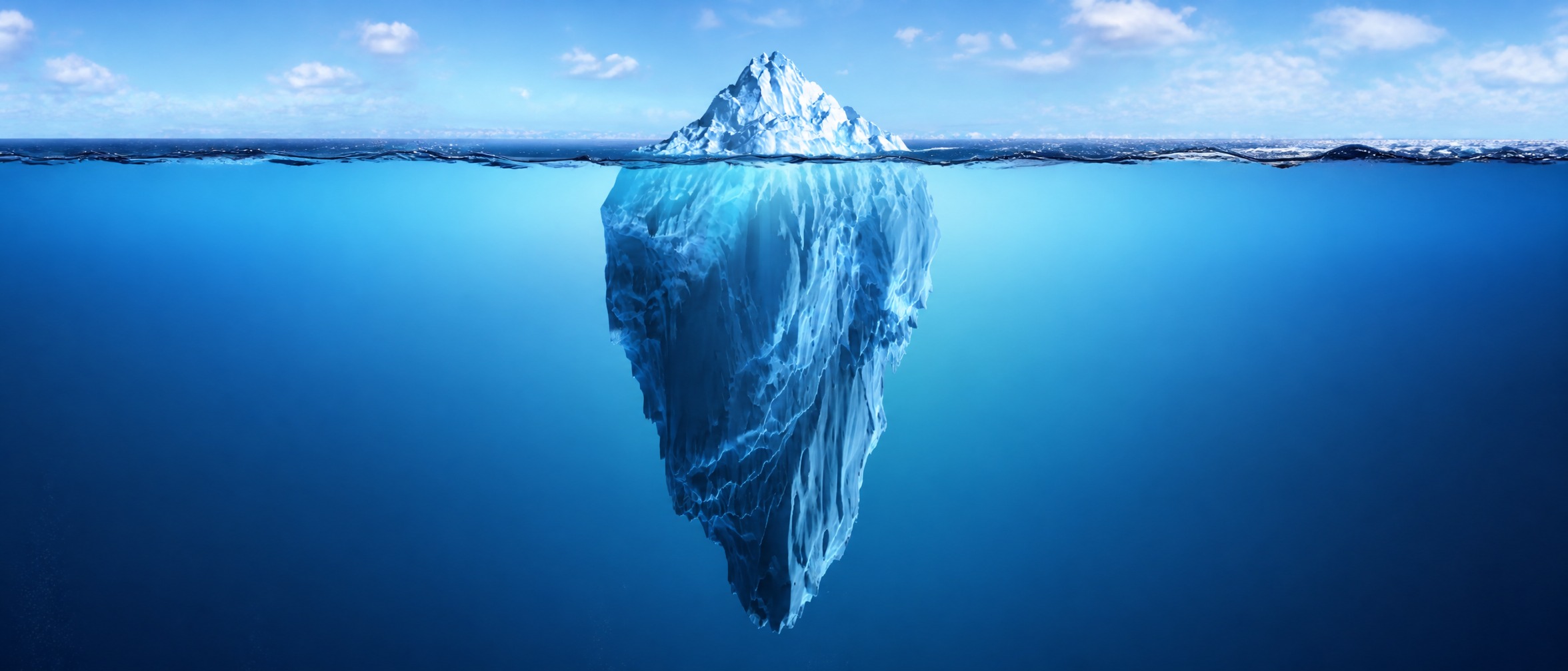 An iceberg split at the waterline - a small visible peak above the surface, a much larger mass hidden below.